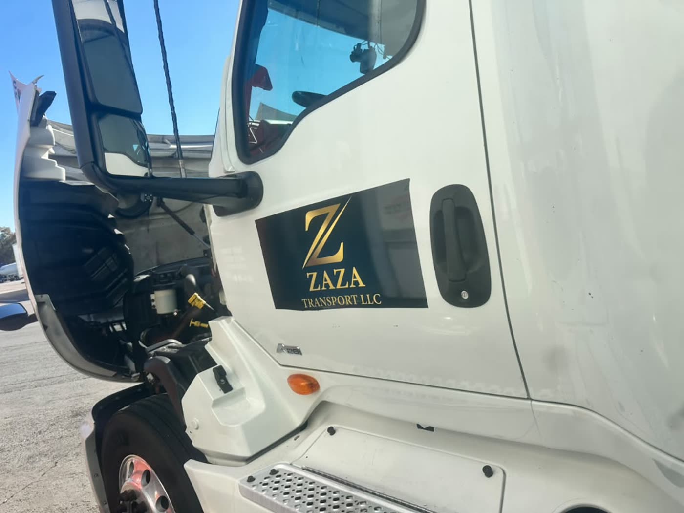 The gold Zaza Transport LLC logo on the door of a white tractor, with the MC and US DOT numbers alongside.